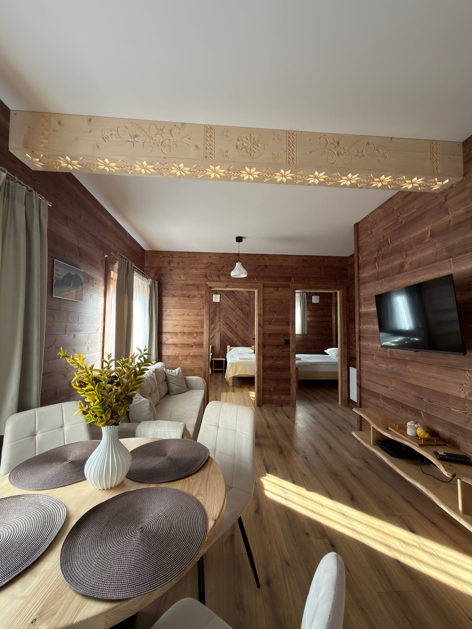 Salon apartamentu Nad potokiem z rzeźbioną belką góralską i wejściem do dwóch sypialni
